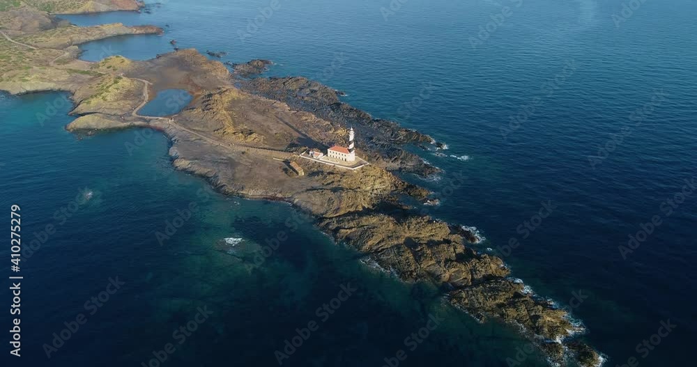 Lighthouse in Menorca surrounded by rocks and water. We can see the lighthouse in the middle of transparent blue water - aerial view 4K Lighthouse in Menorca surrounded by rocks and water. We can see the lighthouse in the middle of transparent blue water - aerial view 4K