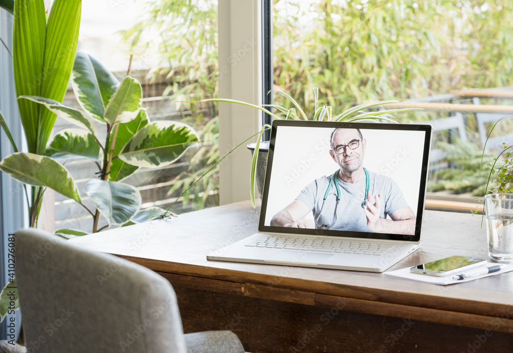 Male doctor giving advice through video call on laptop at home Male doctor giving advice through video call on laptop at home
