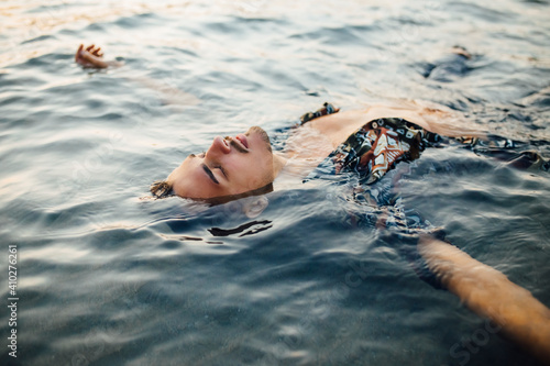 Young man with eyes closed wearing unbuttoned shirt while floating in water photo