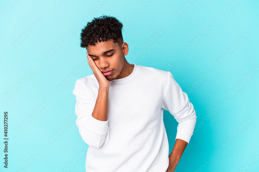 Young african american curly man isolated on blue who is bored, fatigued and need a relax day. Young african american curly man isolated on blue who is bored, fatigued and need a relax day.
