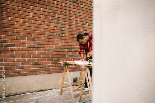 Wallpaper Mural Man using drill machine by brick wall during summer Torontodigital.ca