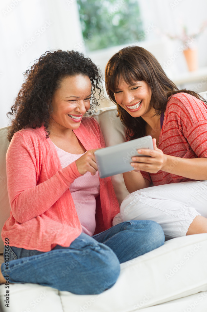Two women sitting on sofa using digital tablets Two women sitting on sofa using digital tablets