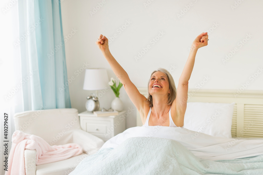 Senior woman stretching in bedroom in morning