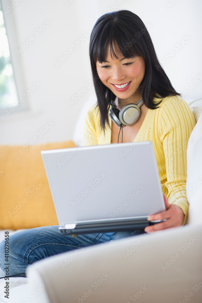 Smiling woman sitting on sofa and using laptop Smiling woman sitting on sofa and using laptop