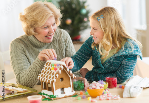 Grandmother with granddaughter (8--9) making gingerbread house photo