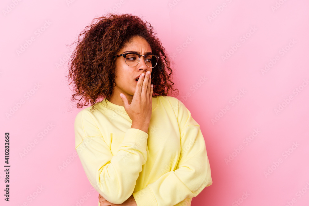 Young african american woman isolated on pink background yawning showing a tired gesture covering mouth with hand. Young african american woman isolated on pink background yawning showing a tired gesture covering mouth with hand.