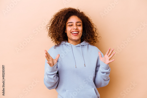 фотографія Young african american woman isolated on beige background laughs out loudly keeping hand on chest