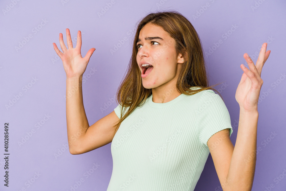 Fototapeta premium Young skinny caucasian girl teenager on purple background screaming to the sky, looking up, frustrated.