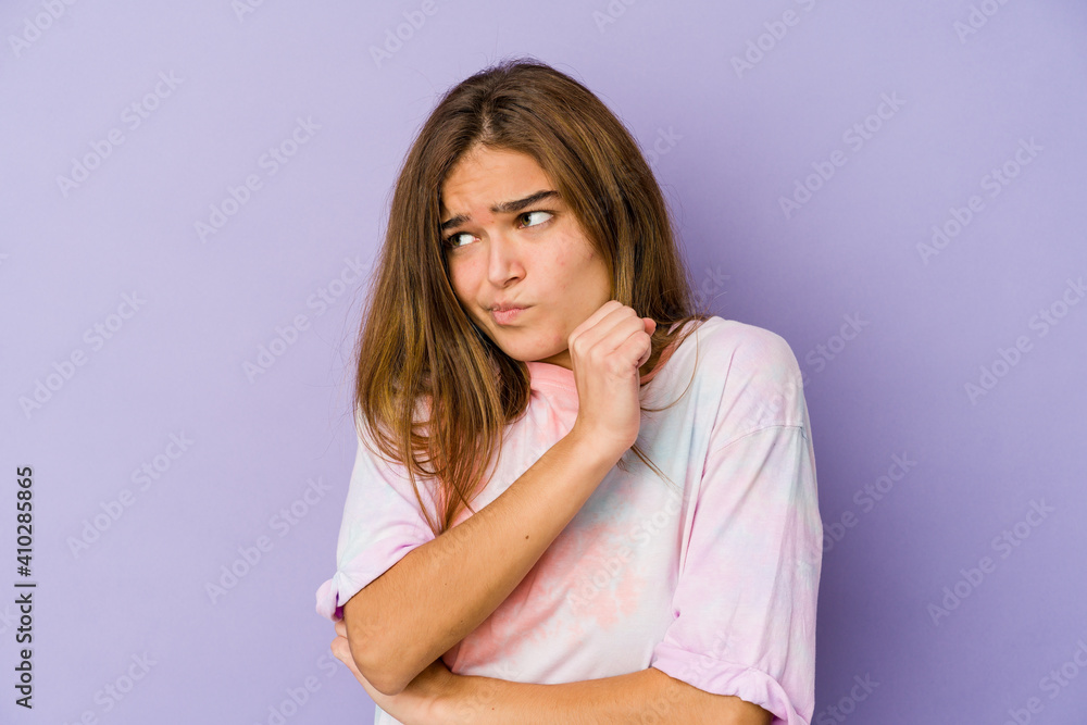 Young skinny caucasian girl teenager on purple background confused, feels doubtful and unsure. Young skinny caucasian girl teenager on purple background confused, feels doubtful and unsure.
