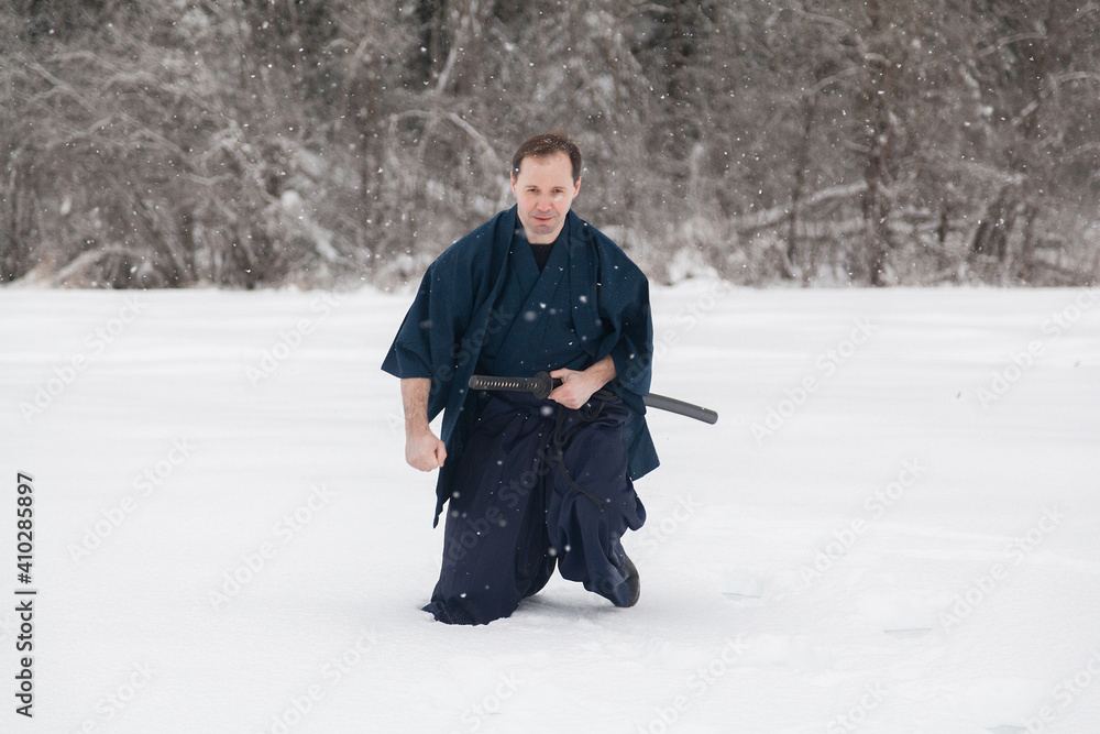 samurai warrior stands with sword and staff in the middle of an empty winter field samurai warrior stands with sword and staff in the middle of an empty winter field