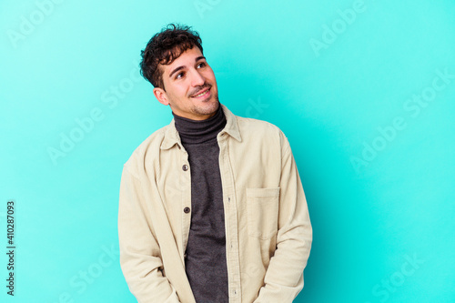 Young caucasian man isolated on blue background relaxed and happy laughing, neck stretched showing teeth.