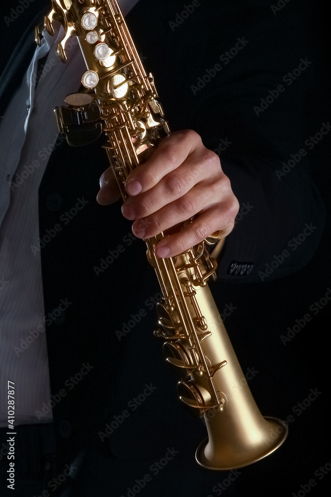 Obraz premium soprano saxophone in the hands of a guy on a black background