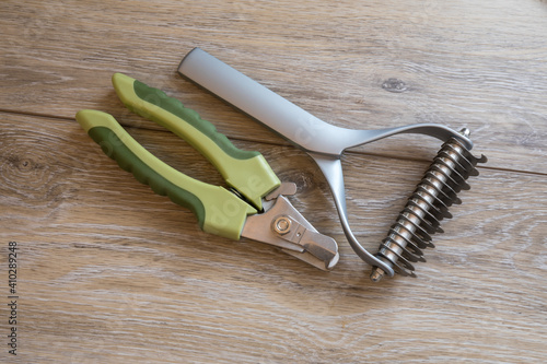 Dog grooming and bathing tools close up. 2 sided undercoat rake, nail clipper.