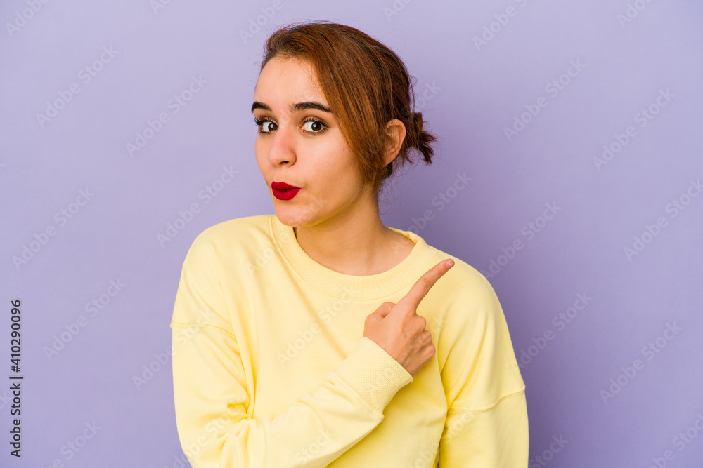 Young arab mixed race woman smiling and pointing aside, showing something at blank space. Young arab mixed race woman smiling and pointing aside, showing something at blank space.
