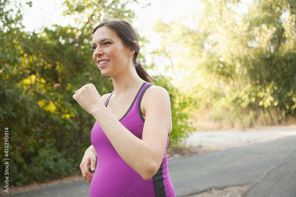 Pregnant mid adult woman in sport clothing jogging Pregnant mid adult woman in sport clothing jogging