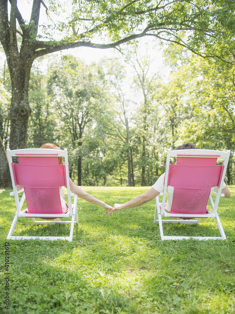 Couple sitting on deck chairs and holding hands Couple sitting on deck chairs and holding hands