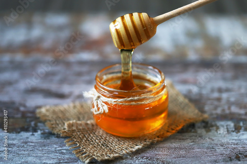Selective focus. Jar of honey. Honey stick. Transparent honey. Liquid honey.