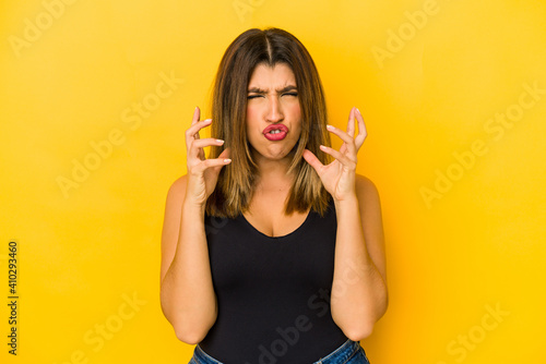 Young indian woman isolated on yellow background upset screaming with tense hands.