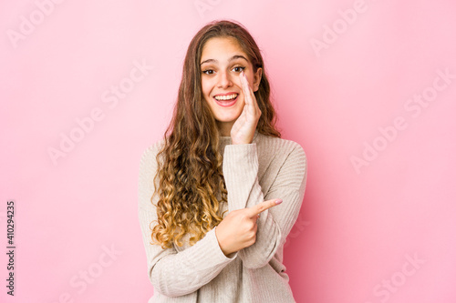 Young caucasian woman saying a gossip, pointing to side reporting something.