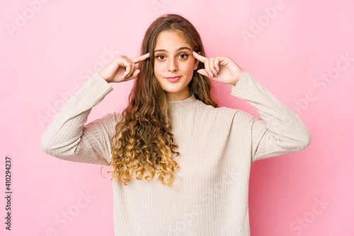 Young caucasian woman focused on a task, keeping forefingers pointing head.