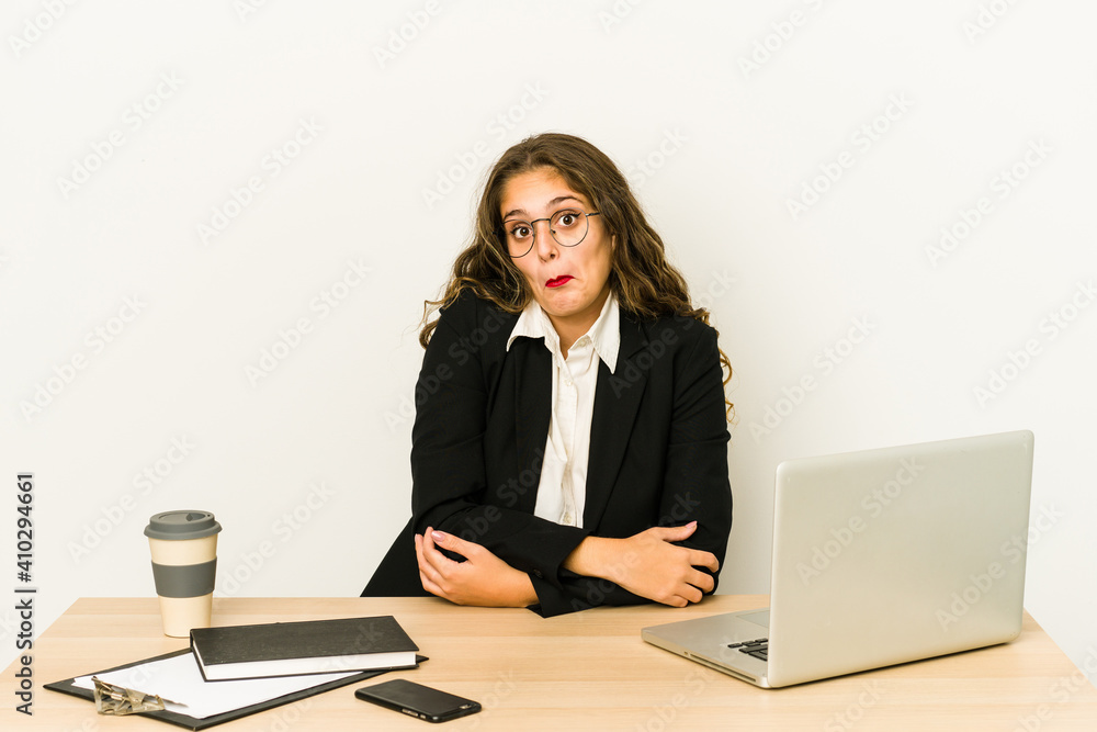 Young caucasian business woman working on her desktop isolated shrugs shoulders and open eyes confused. Young caucasian business woman working on her desktop isolated shrugs shoulders and open eyes confused.