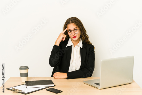 Young caucasian business woman working on her desktop isolated pointing temple with finger, thinking, focused on a task.