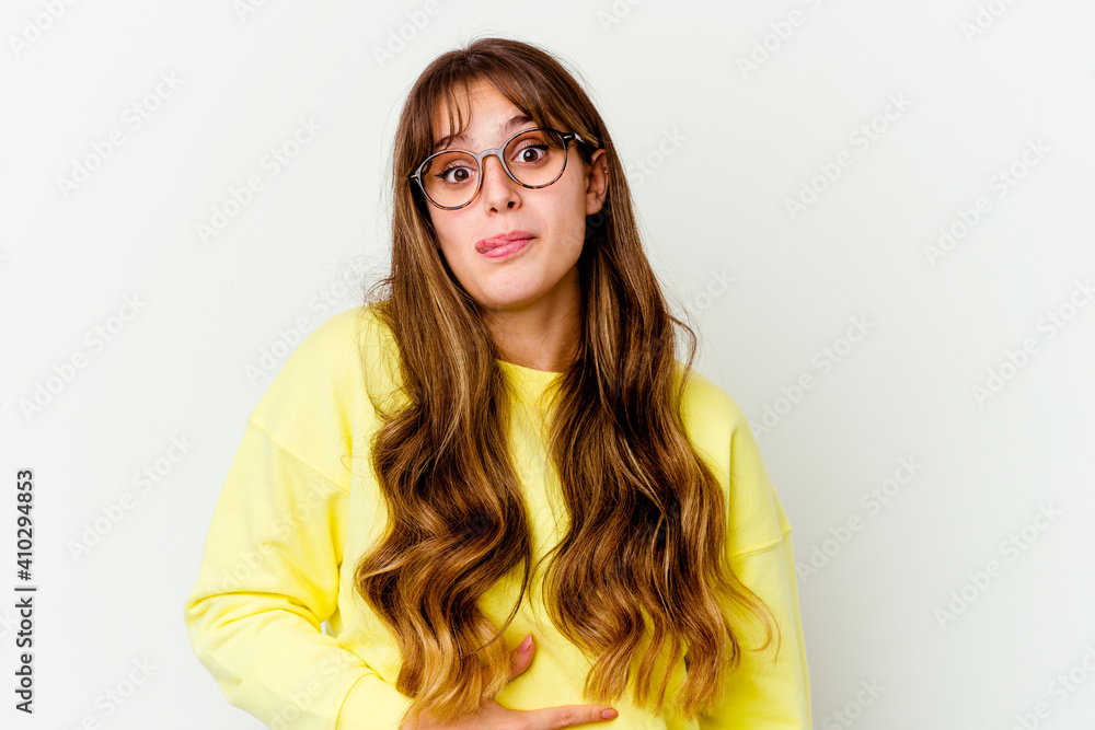 Young caucasian cute woman isolated on white background touches tummy, smiles gently, eating and satisfaction concept.