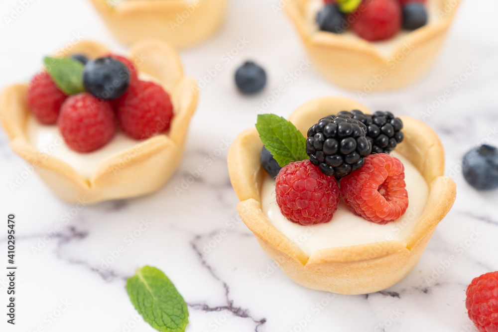Delicious pastry mini fruit cream cheese pies or tart cakes with fresh raspberry, blueberry and blackberry Delicious pastry mini fruit cream cheese pies or tart cakes with fresh raspberry, blueberry and blackberry