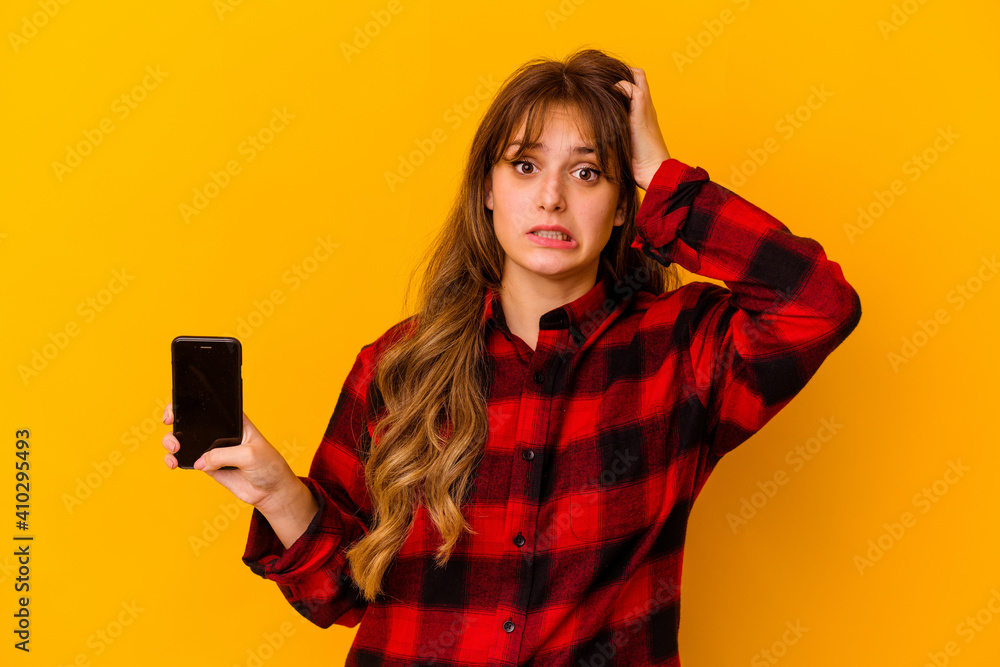 Young caucasian woman holding phone isolated on yellow background being shocked, she has remembered important meeting. Young caucasian woman holding phone isolated on yellow background being shocked, she has remembered important meeting.