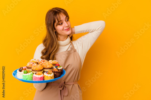 Young pastry chef woman isolated on yellow background touching back of head  thinking and making a choice.