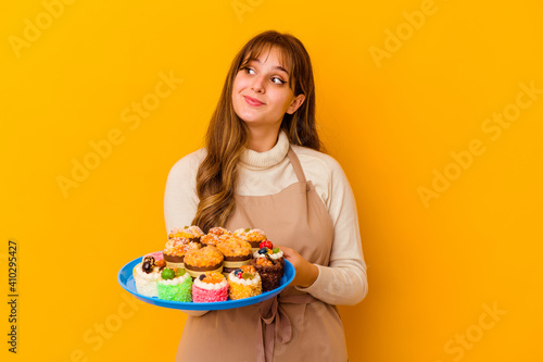 Young pastry chef woman isolated on yellow background dreaming of achieving goals and purposes