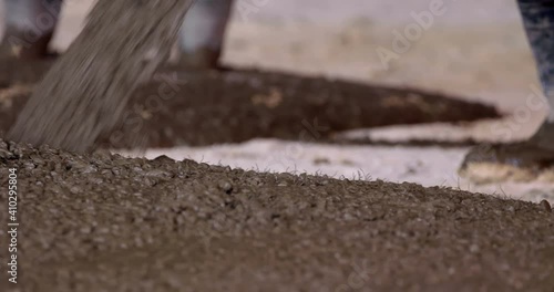 On a construction site, workers from an automatic mixer pour concrete reinforced with metal fibers onto the surface prepared for screed 