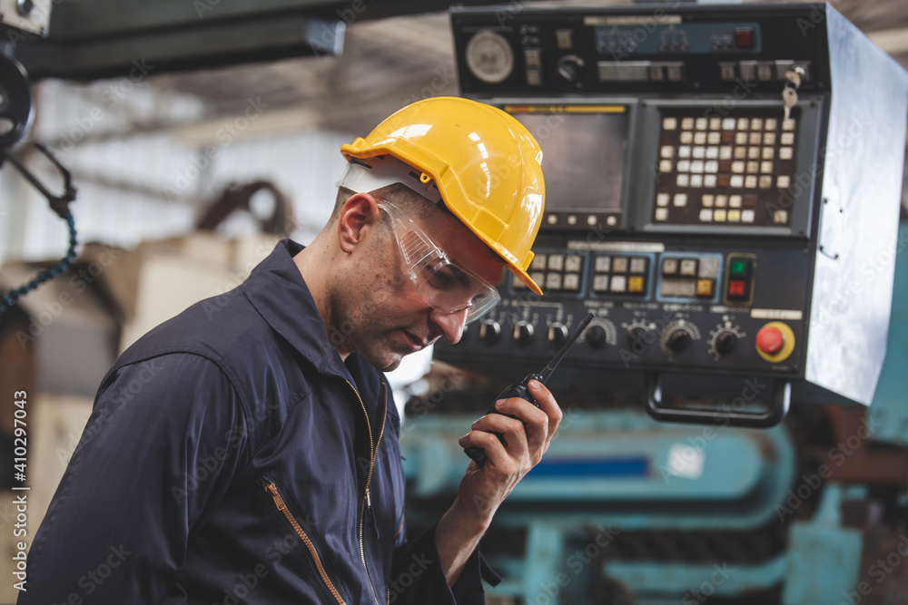 Portrait of male worker talking on radio phone calling team worker. machine technology invention industry manufacturing factory Portrait of male worker talking on radio phone calling team worker. machine technology invention industry manufacturing factory