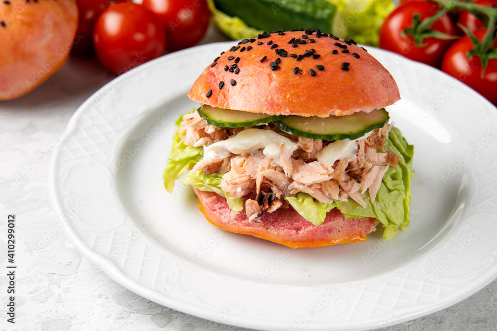 Delicious burger of pink dough with salmon on a white plate. Healthy seafood concept. Omega 3 fats. Brain food