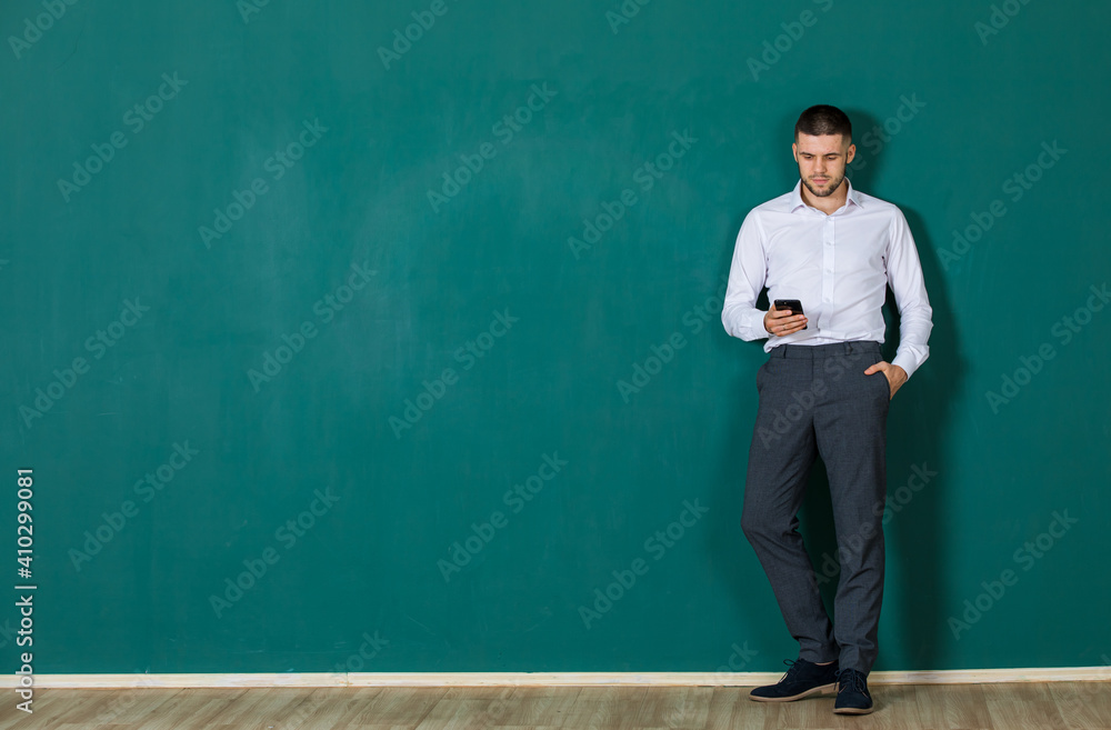 A business man in casual clothe standing and using smart phone on green background A business man in casual clothe standing and using smart phone on green background