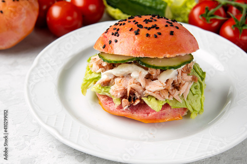 Delicious burger of pink dough with salmon on a white plate. Healthy seafood concept. Omega 3 fats. Brain food