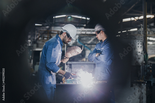Industrial Worker at the factory welding. Workers wearing industrial uniforms and Welded Iron Mask at factory welding plants