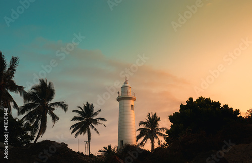 Lighthouse glowing in the evening sunset, Galle Dutch fort, Palm trees, and the cost scenic landscape photograph. Sri Lanka's oldest light station and tourist attraction and a world heritage site.