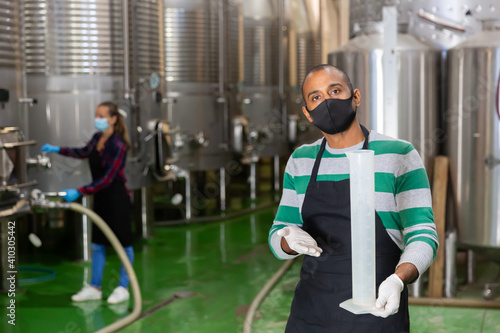 Man in protective mask with beaker in a winery shop