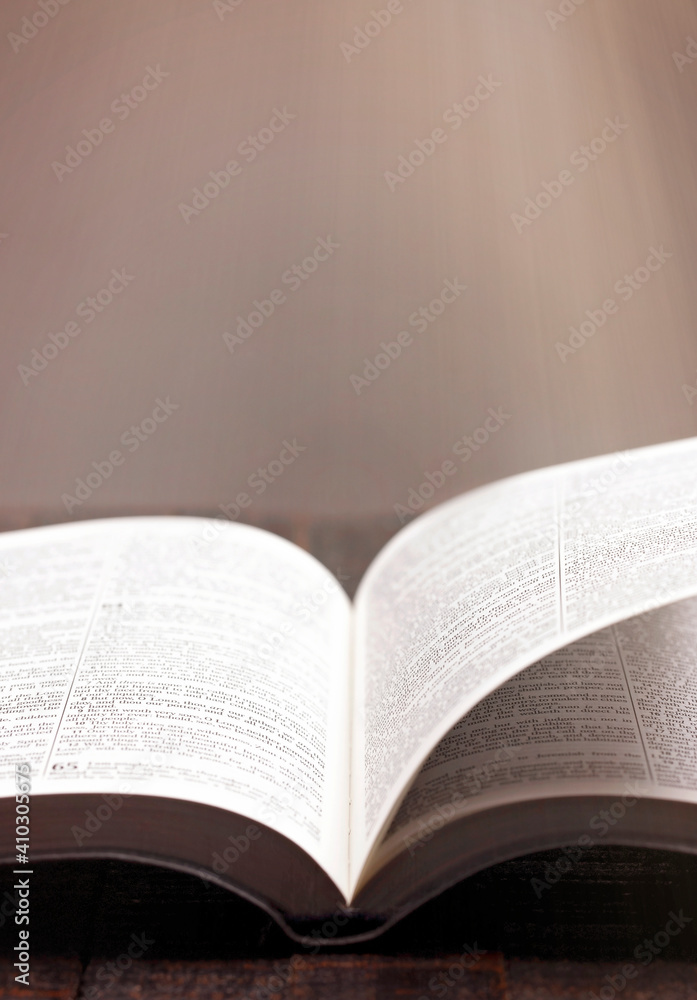 Fototapeta premium A Bible Open on a Rustic Wooden Table with Pages Blowing Open