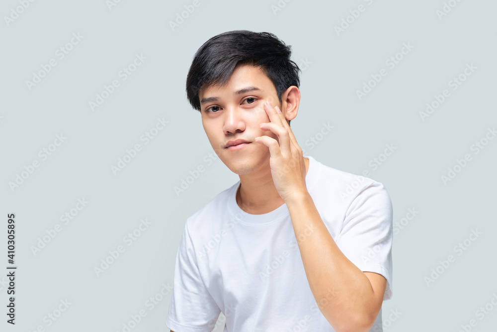 A young man examining the health of his face while looking in the mirror. A young man examining the health of his face while looking in the mirror.