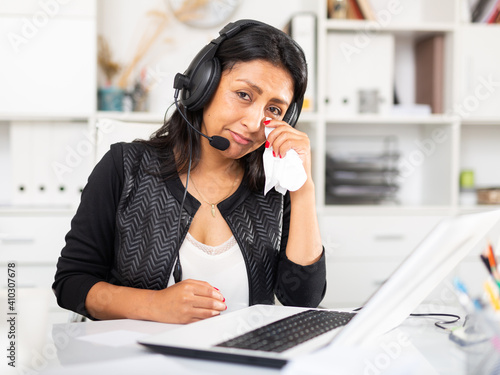 Portrait of frustrated tearful Hispanic woman customer support phone operator at workplace