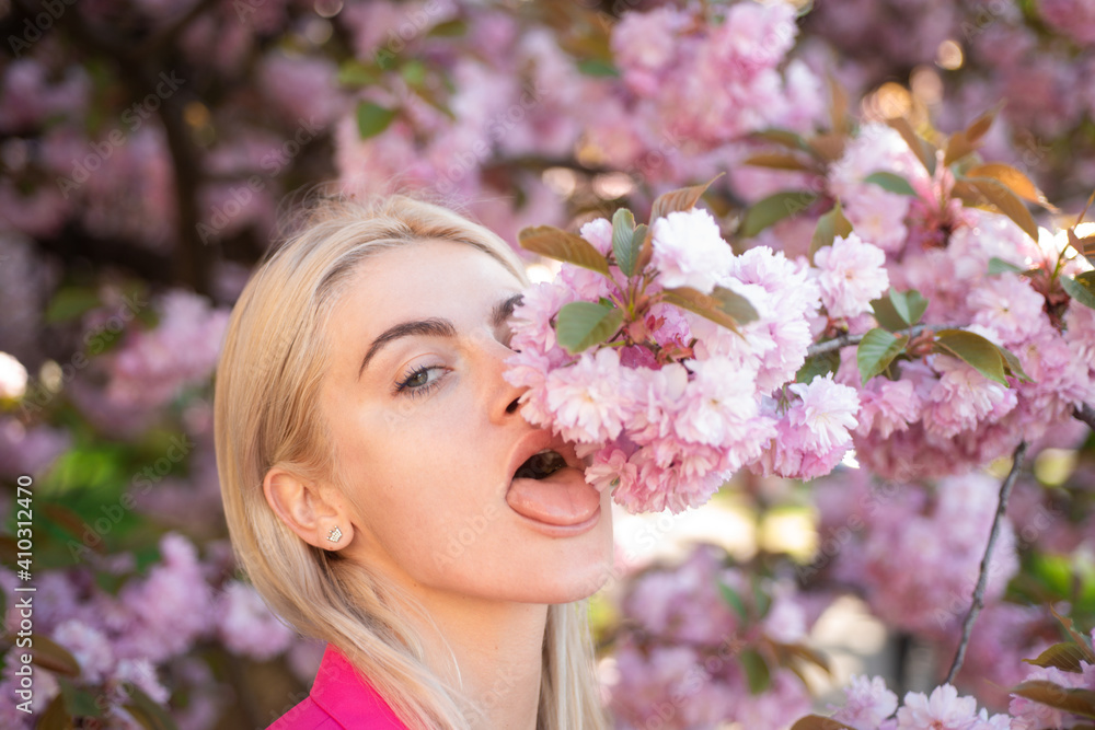 Obraz premium Girl in in blossoms cherry sakura. Outdoor portrait of beautiful sensual fashion girls posing near blooming tree with pink flowers.