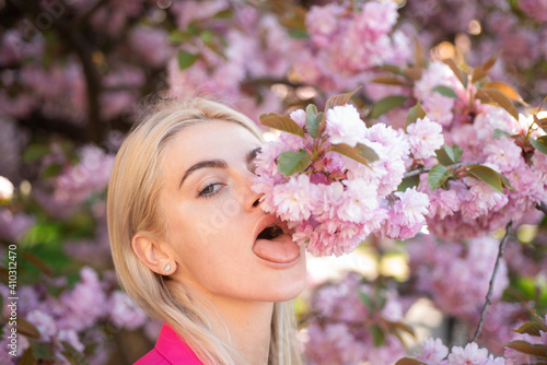 Girl in in blossoms cherry sakura. Outdoor portrait of beautiful sensual fashion girls posing near blooming tree with pink flowers.