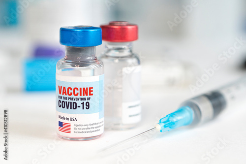 Medical glass vial and plastic syringe for injection on white table with blue gradient background. Concept of vaccination in United States of America. Copy space. photo