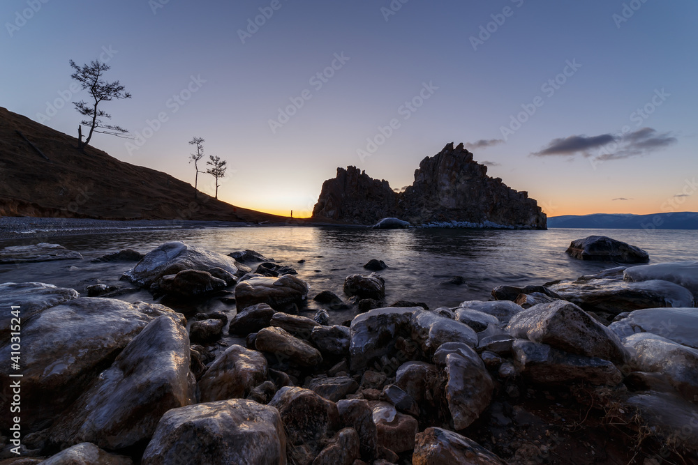 Shore of Baikal lake with stones covered with ice in November
