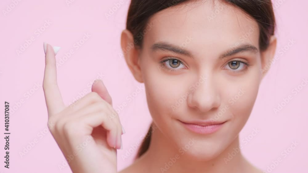 Close-up beauty portrait of young fresh looking woman with perfect skin who shows a drop of a cream on her finger and looks at the camera | Cream commercial concept Close-up beauty portrait of young fresh looking woman with perfect skin who shows a drop of a cream on her finger and looks at the camera | Cream commercial concept