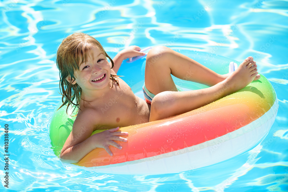 Kids Swimming with Swim Ring. Happy kid playing with colorful swim ring in swimming pool on summer day. Child water toys. Children play in tropical resort. Family beach vacation.