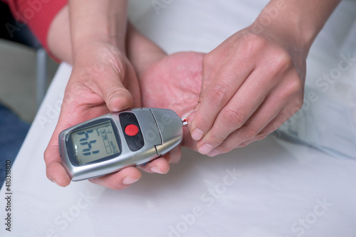 closeup on the hands of a latin woman doctor doing a test to measure sugar levels in middle-aged man as a prevention method to avoid suffering from diabetes