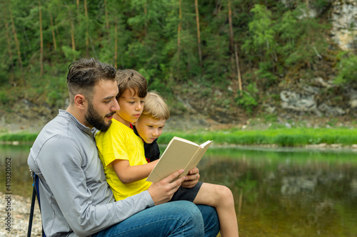 Father reading to his sons on vacation in park